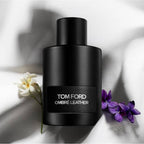 Black Tom Ford Ombre Leather perfume bottle with flowers on a light background