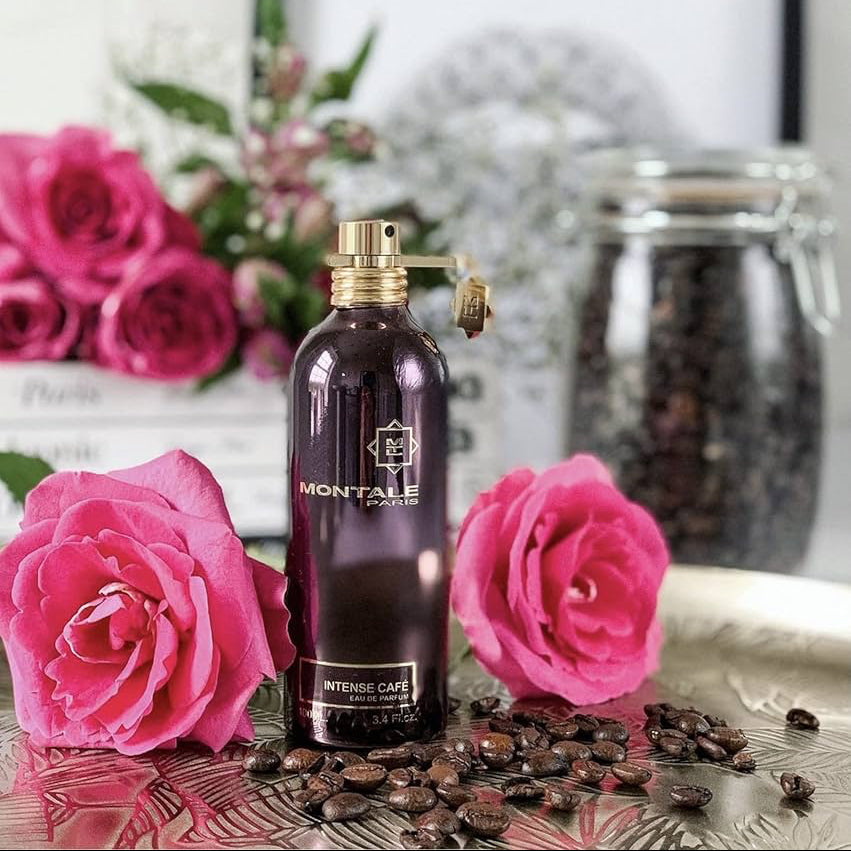 Montale Paris perfume bottle with pink roses and coffee beans on a reflective surface