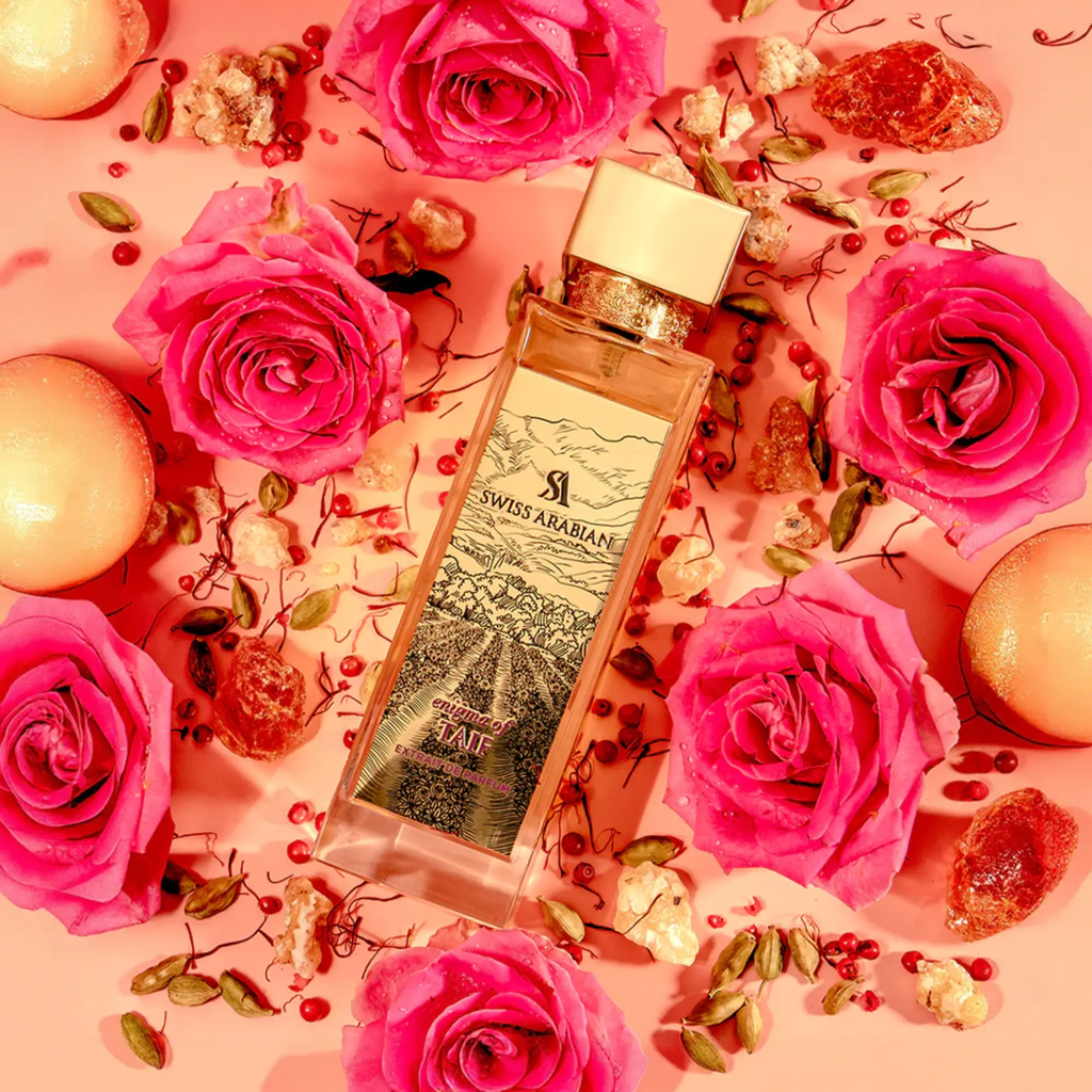 Swiss Arabian Enigma of Taif perfume bottle surrounded by pink roses on a pink background