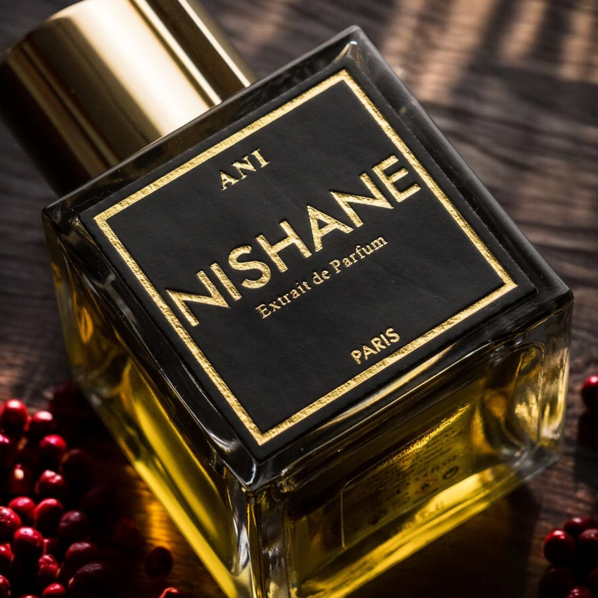 Nishane perfume bottle with gold cap on a wooden surface