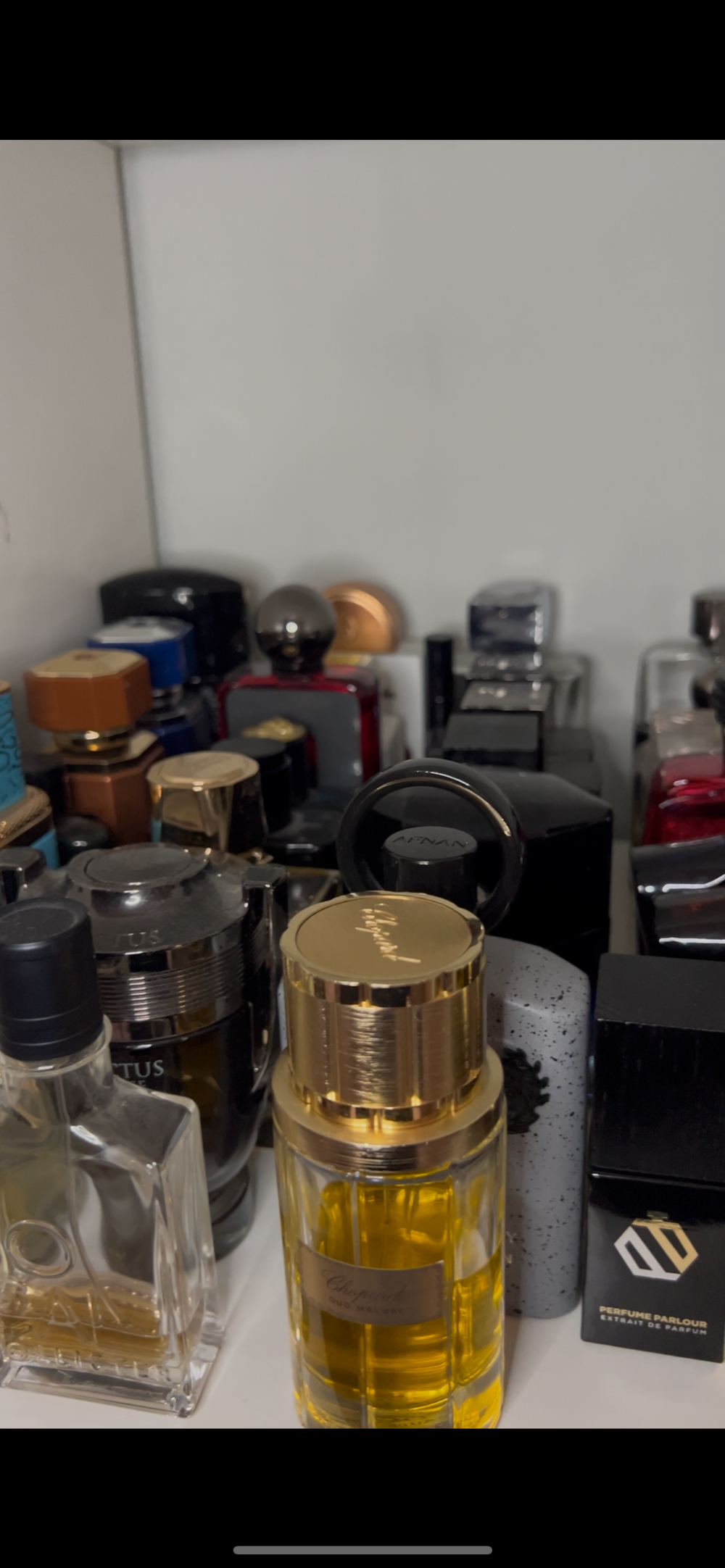 Collection of perfume bottles on a shelf with a white wall background