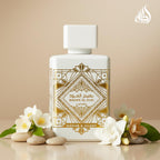Perfume bottle Lattafa Bade’e Al Oud Honour & Glory with decorative label surrounded by flowers on a beige background