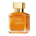 Perfume bottle with gold cap Maison Francis Kurkdjian Grand Soir and orange liquid on a white background