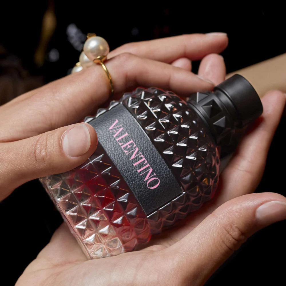 Hand holding a Valentino perfume bottle with a textured design