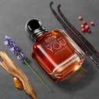 Perfume bottle with vanilla beans, lavender, and red berries on a gray background