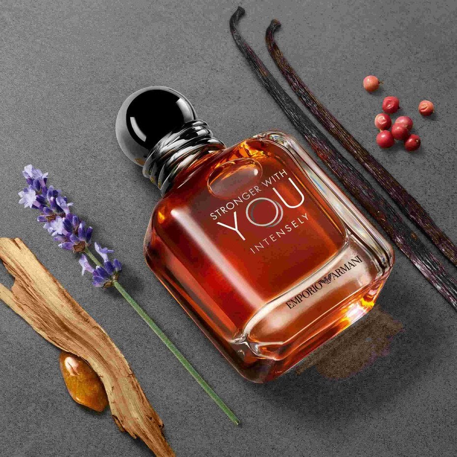 Perfume bottle with vanilla beans, lavender, and red berries on a gray background