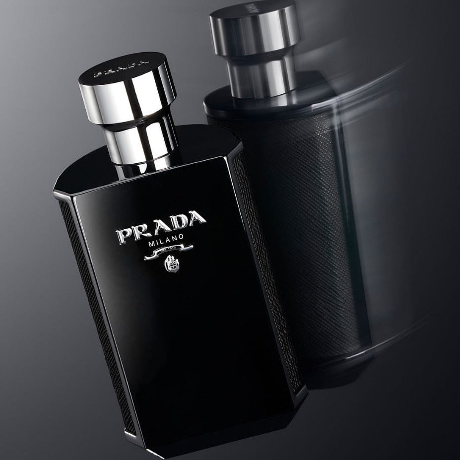 Two black Prada Milano perfume bottles on a dark background